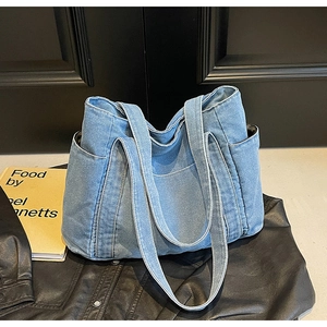 Detailed close-up of large blue denim tote bag texture with side pocket and stitching