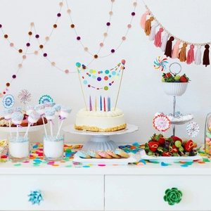 Close-up of colorful party tassels and polka dot cake toppers on a bright dessert table