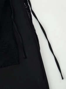 Detailansicht aus eleganter schwarzer Spitze und glatter Satinstruktur mit Kordelzug