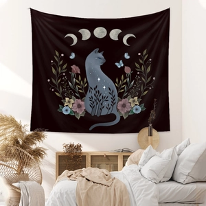 Detail of bohemian black cat tapestry with moon phases and flowers hanging in bedroom