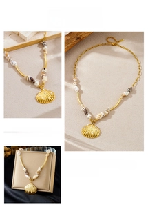 Detail of gold shell pendant necklace with white beads and natural conch on sand background
