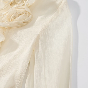 Macro detail of handmade 3D floral accents on cream textured lantern sleeve dress
