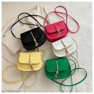 Flat lay of small tassel square bags in five colors including black, pink, white, and green