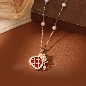 Detail of gold plated pearl necklace with red zircon lucky bag pendant and fine chain
