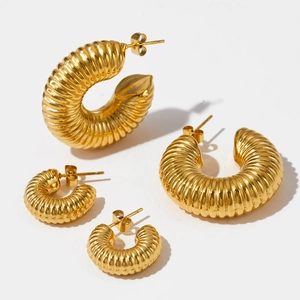 Macro view of gold twisted C-shape hoop earrings in two sizes with metallic luster