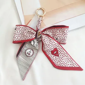 Detail of camellia silk scarf bow keychain with red heart print and gold clasp
