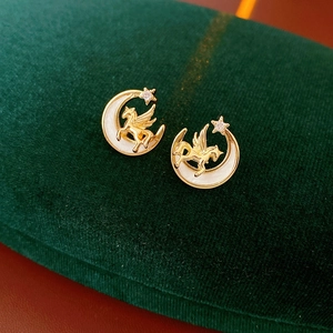 Detailed close-up of golden vintage moon and pegasus earrings with sparkling zircon