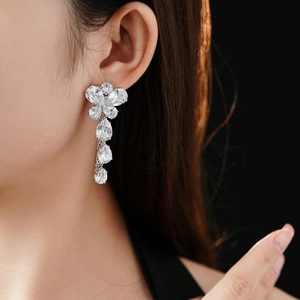 Macro shot of silver tassel earrings with zircon flower studs and drop pendants on model
