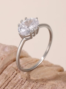 Macro shot of a silver oval zircon ring on a natural stone with elegant lighting