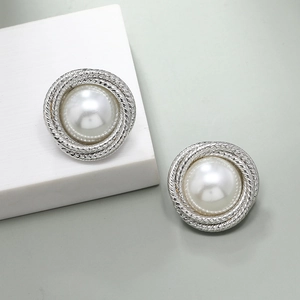 Minimalist silver wrap earrings with white baroque pearls shown on a geometric stand