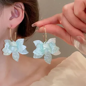 Boucles d'oreilles créoles fleurs en résine avec pétales marbrés bleu clair et métal doré