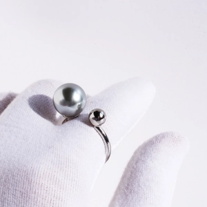 Minimalist U-shaped open ring featuring a grey pearl and silver ball on a gloved finger