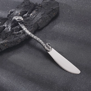 Macro shot of silver snake-shaped handle knife on rustic wood background