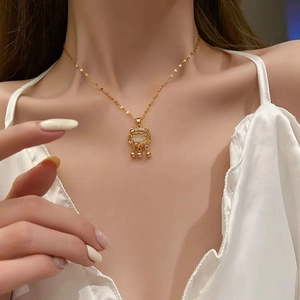 Close-up of a gold Ruyi lock necklace with three delicate bell charms on a female model