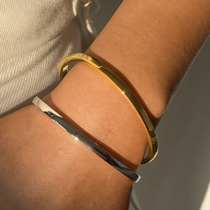 Polished stainless steel bangle set in gold and silver finish on model's wrist