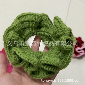 Detailed close-up of a handmade green knitted ruffle scrunchie showing soft yarn texture