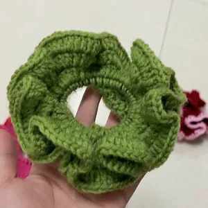 Detailed close-up of a handmade green knitted ruffle scrunchie showing soft yarn texture