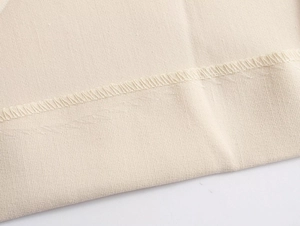 Macro shot showing off-white fabric texture and detailed overlock stitching craftsmanship