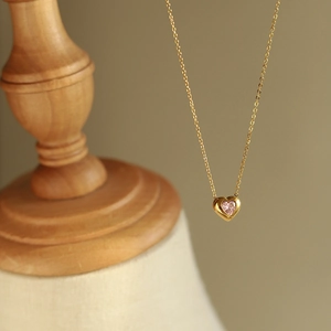 18K gold plated titanium necklace featuring a pink heart pendant on a wooden stand