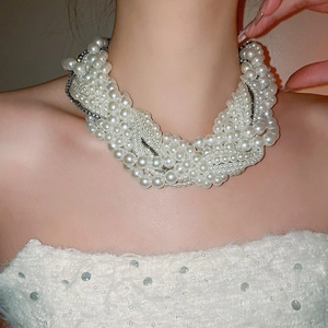 Close-up of layered pearl necklace with rhinestone chains on model's neckline