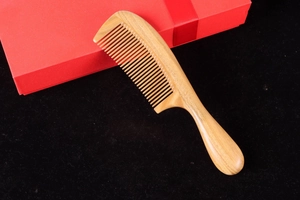 Close-up of a premium thick green sandalwood comb with natural wood grain and red gift box