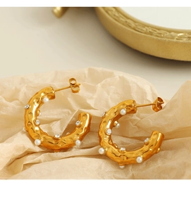 Detailed macro view of 18K gold plated C-shape earrings with pearls and crystals