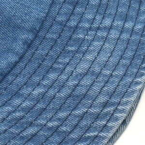 Detailed macro view of parallel stitching on blue washed denim fisherman bucket hat