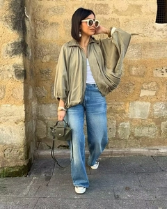 Look urbain de bomber vert olive porté avec un jean bleu et un débardeur blanc élégant