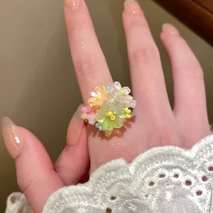 Detail of beaded flower ring with pastel petals and green accent on model with lace