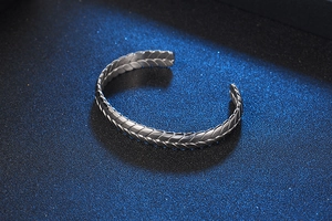 Primer plano detallado del patrón de espigas en un brazalete de acero plateado