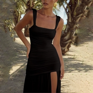 Detail of a black backless dress with ruched design and high slit at a beach