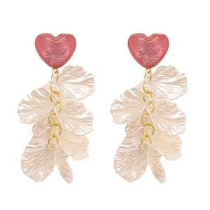 Boucles d'oreilles cœur en résine avec pétales blancs et détails dorés sur fond blanc