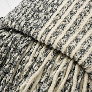 Close-up of thick chenille knit texture with grey striped patterns and long fringe edges