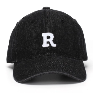 Close-up of white embroidered letter R on black washed denim baseball cap texture