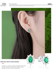 Macro view of S925 silver halo stud earrings with oval emerald center and small diamonds