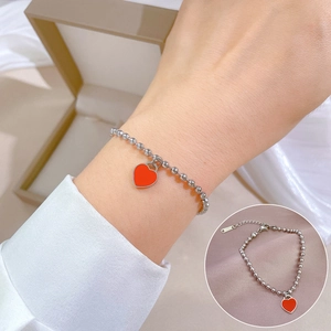 Detailed close-up of a silver beaded bracelet featuring a red enamel heart pendant