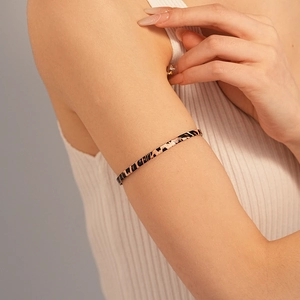 Close-up of a double-layer leopard print arm cuff on a female model wearing a white top