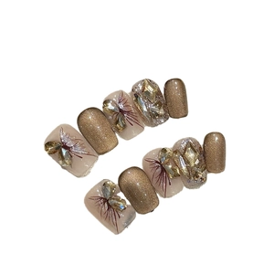Handmade press-on nails featuring champagne glitter and 3D rhinestone butterfly designs