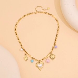 Collier doré avec pendentifs cœur turquoise, fleur rose et soleil sur fond beige