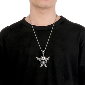 Close-up of a silver punk skull and crossed pistols pendant worn on a black t-shirt