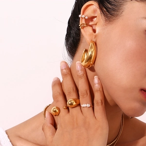 Close-up of minimalist 18K gold plated crescent hoops and pearl jewelry set on model