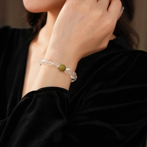 Détail de perles en cristal clair et d'une pierre de jade verte sur le bracelet