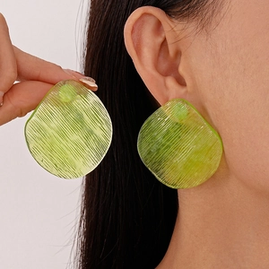 Macro detail of lime green resin earrings with vertical textures and translucent finish
