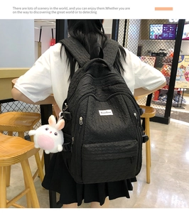 Gros plan d'un sac à dos noir texturé à vagues avec un charmant lapin en peluche blanc