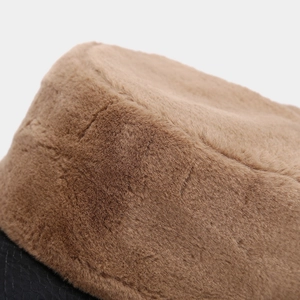 Detail of plush brown faux fur joined with a textured black leather brim on a winter cap