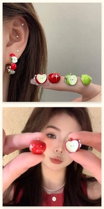 Detail of red and green asymmetrical apple stud earrings with enamel and silver pins