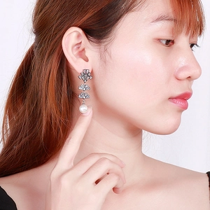 Detail of elegant pearl drop earrings with sparkling rhinestones on model's profile