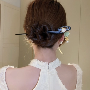Close-up of a wooden hair stick with white rabbit ornament and pearl tassels on a bun