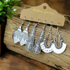 Detailed view of three pairs of vintage silver-tone bohemian earrings on wooden background