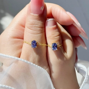 Close-up of gold chain rings with oval purple zircon for mother and daughter set